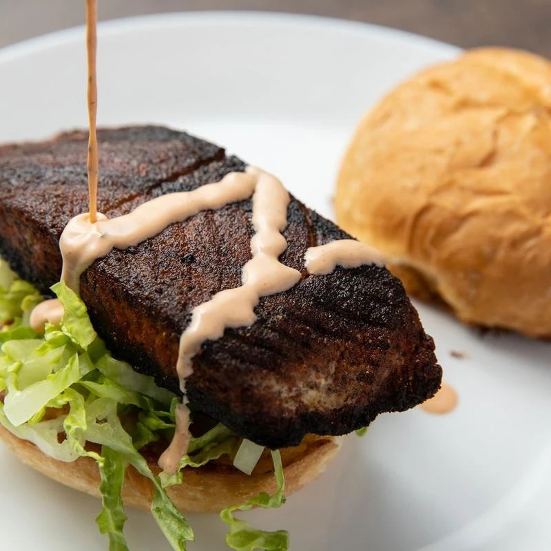 Blackened salmon sandwich with lettuce, closeup