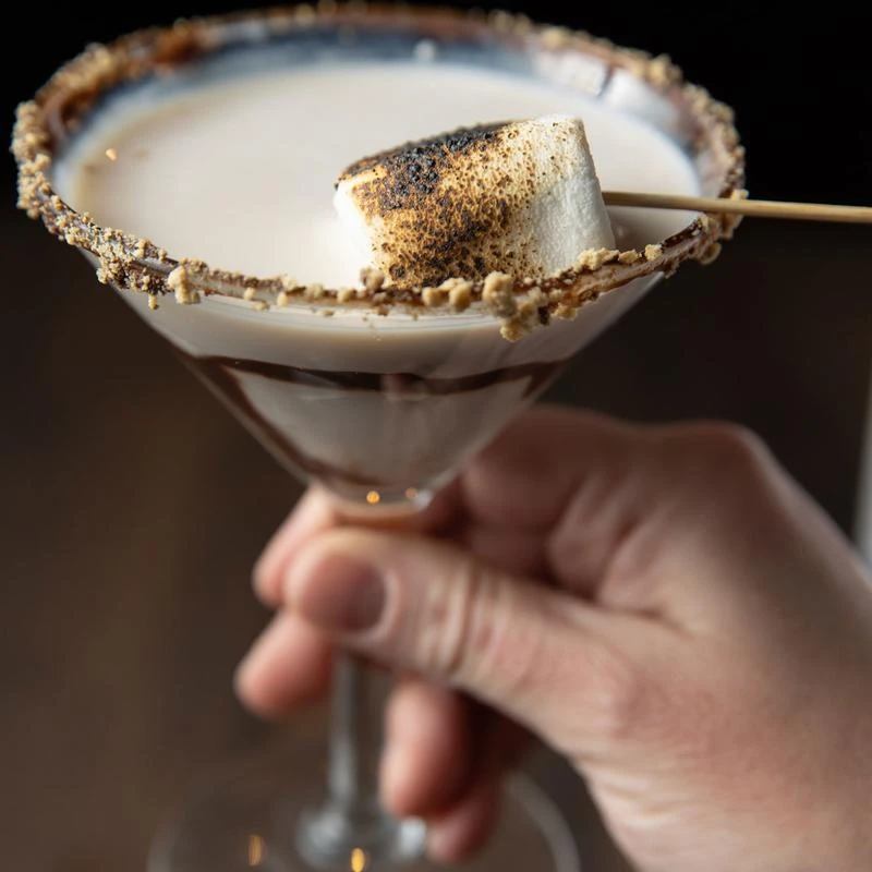 A hand holding a glass of Smoretini cocktail